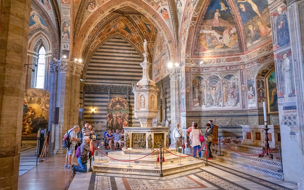Tourists inside Siena Cathedral admiring frescoes and architecture, Italy.