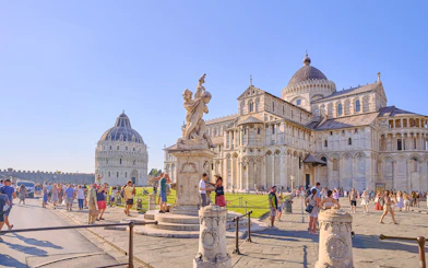 Pisa Cathedral and Baptistery with tourists exploring the square.