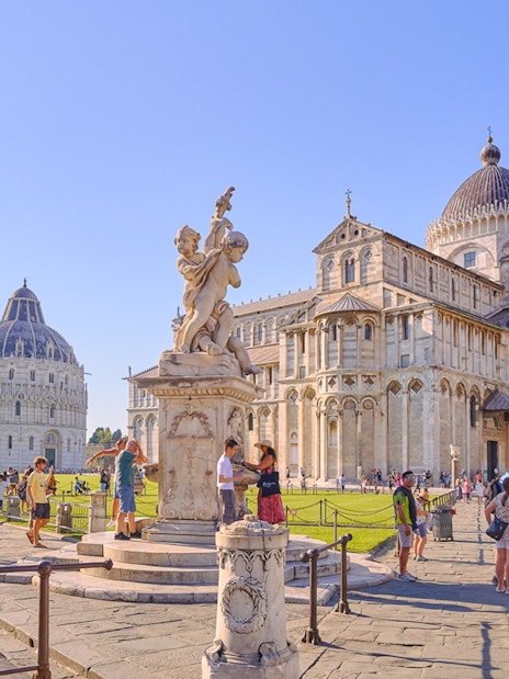 Pisa Cathedral and Baptistery with tourists exploring the square.