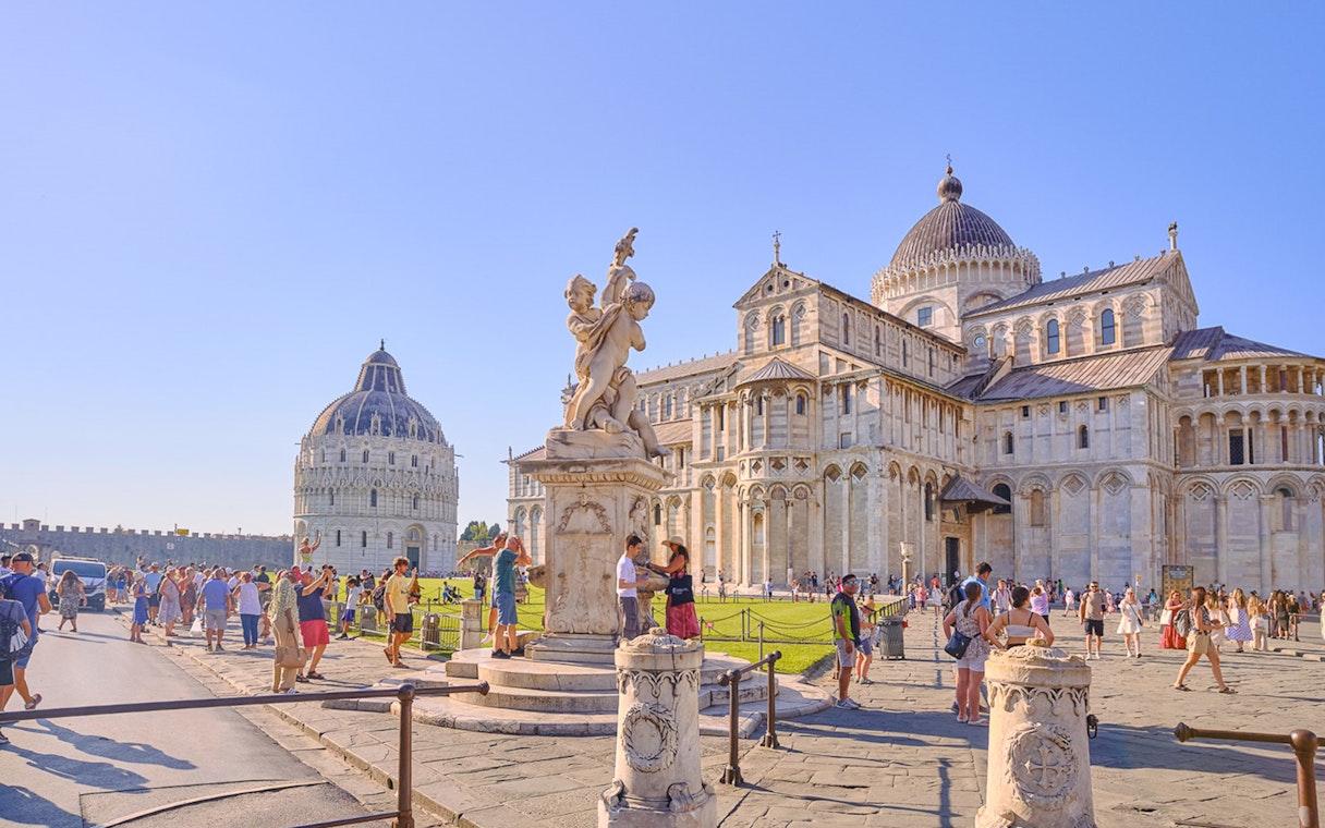 Pisa Cathedral and Baptistery with tourists exploring the square.