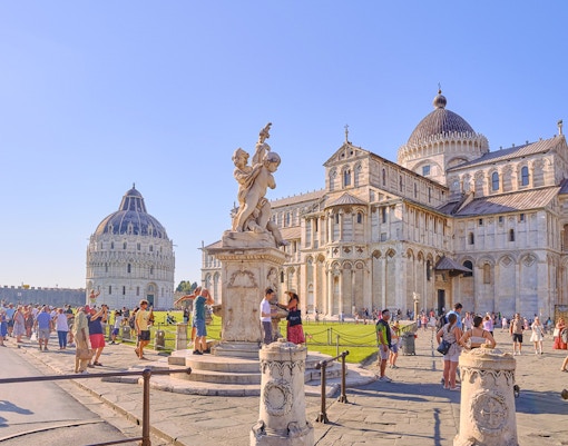 Pisa Cathedral and Baptistery with tourists exploring the square.