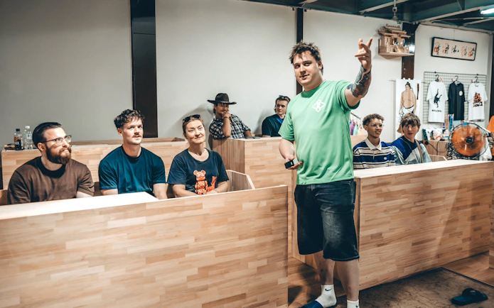 Instructor in green t-shirt leading interactive session with visitors seated at wooden benches.