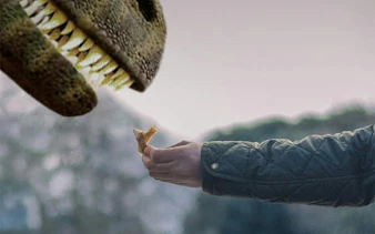 Hand feeding a dinosaur model at Dinos Alive: The Immersive Experience in Toulouse.