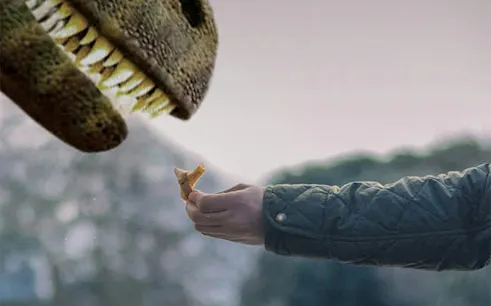 Hand feeding a dinosaur model at Dinos Alive: The Immersive Experience in Toulouse.