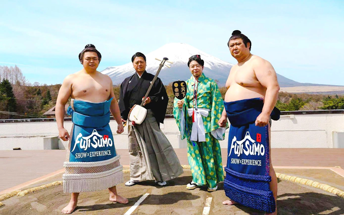 Sumo wrestlers and performers at Fuji Sumo Show in Yamanashi with Mount Fuji in the background.