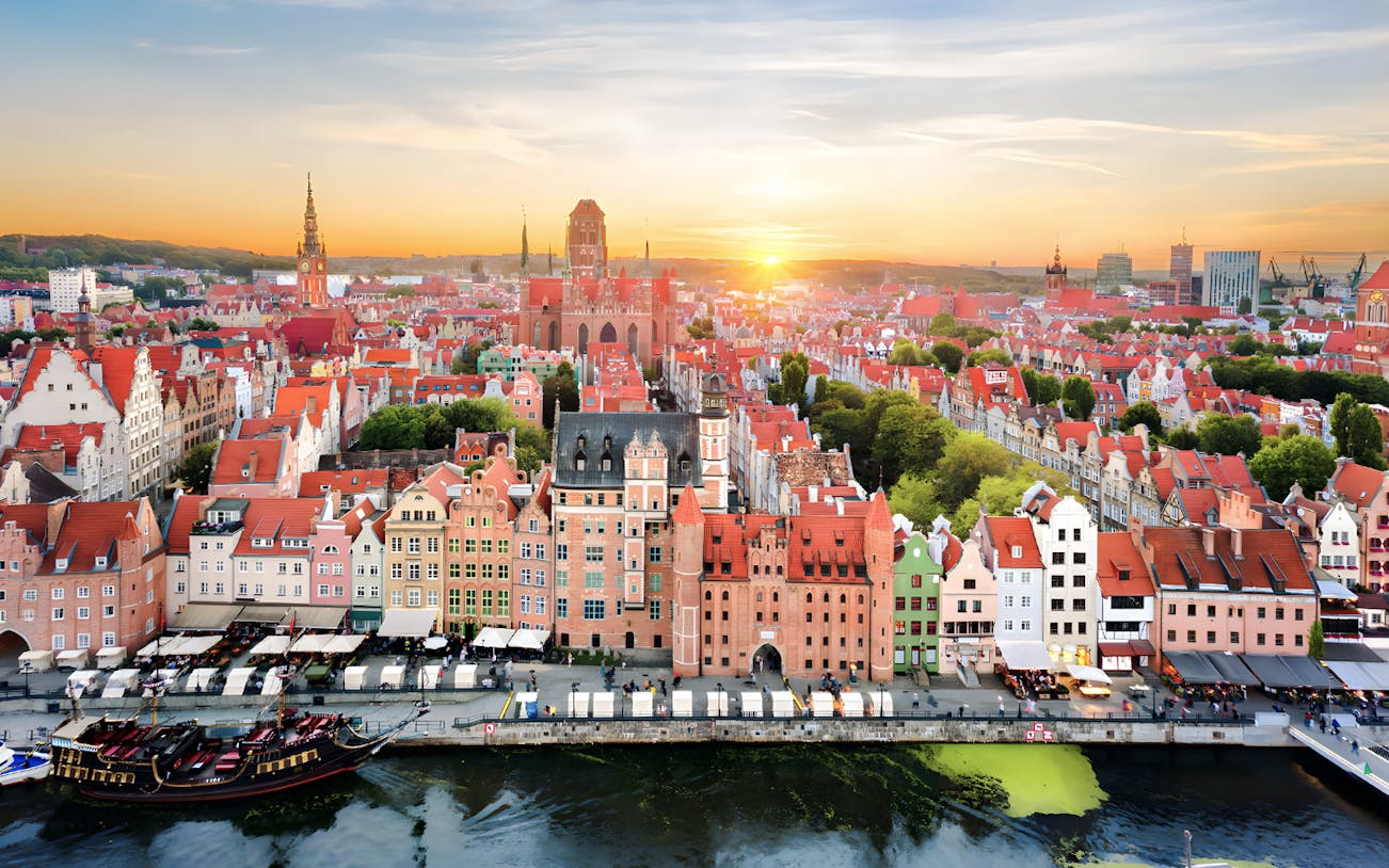 Gdańsk cityscape with colorful buildings along the Motława River at sunset.