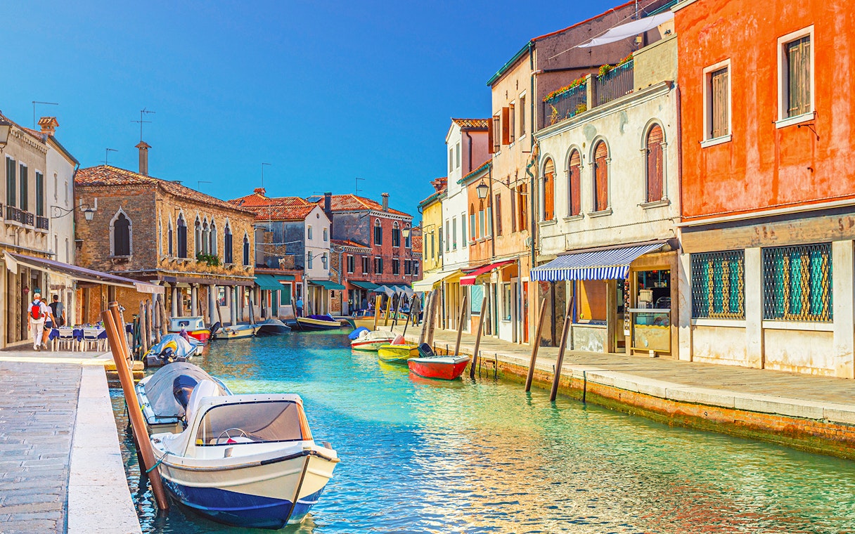 Canal view with colorful buildings and boats in Burano, Italy.