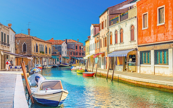 Canal view with colorful buildings and boats in Burano, Italy.