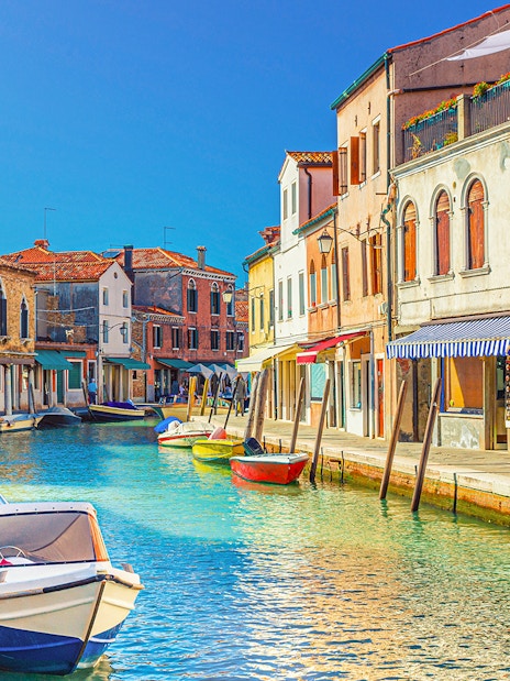 Canal view with colorful buildings and boats in Burano, Italy.