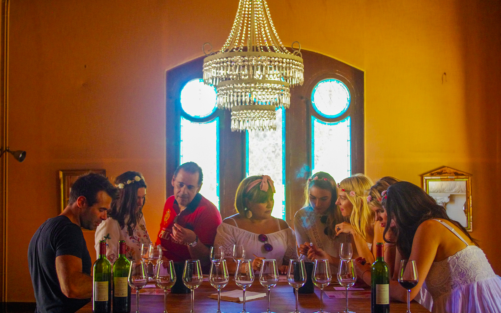 Group wine tasting at a Saint Emilion winery with chandelier and stained glass windows.