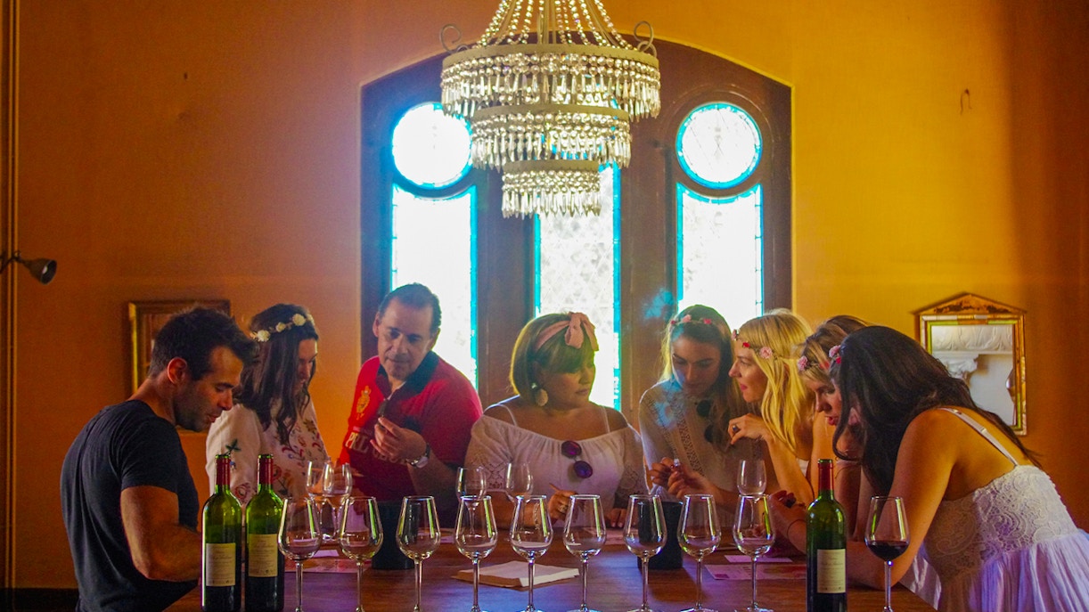 People having lunch in Saint Emilion vineyard with historic village buildings in the background.