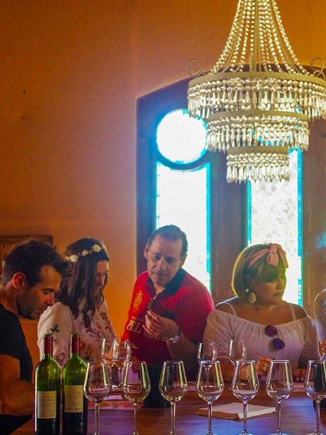 Group wine tasting at a Saint Emilion winery with chandelier and stained glass windows.
