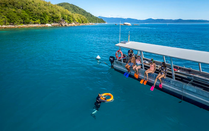 Tourists snorkeling from a boat at Fitzroy Island, Australia.