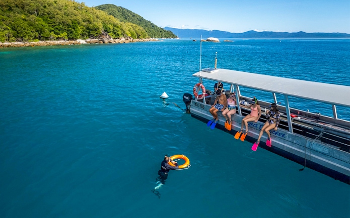 Tourists snorkeling from a boat at Fitzroy Island, Australia.