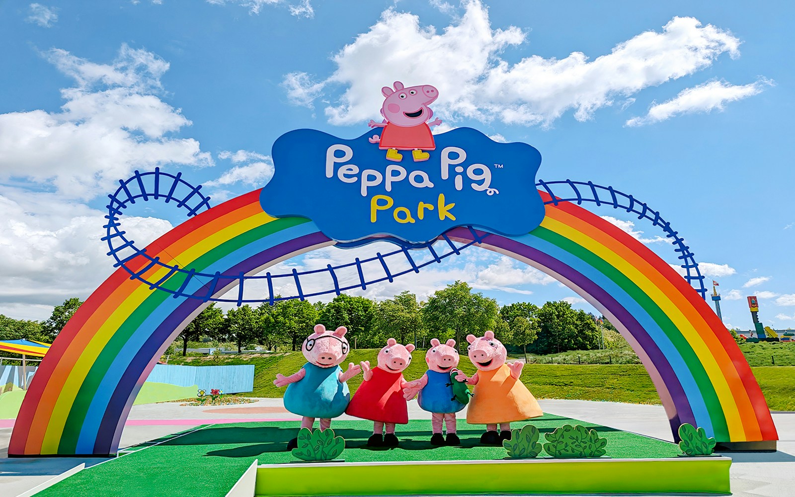 Staff in Peppa Pig costumes under rainbow arch at Peppa Pig Park, Guntzburg.