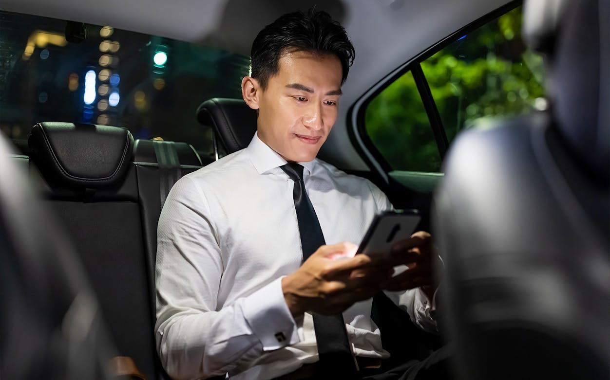 Private transfer passenger using phone in car from Kansai Airport.