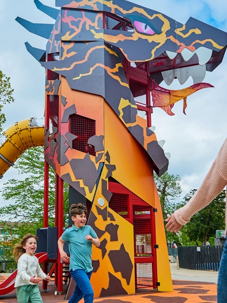 Children playing near dragon-themed slide at LEGOLAND® Windsor Resort.