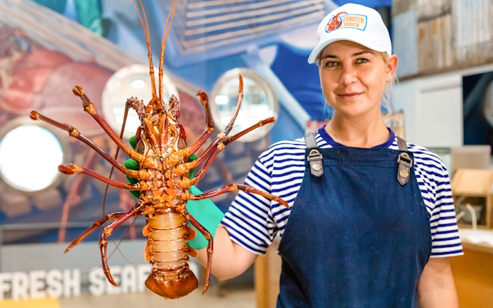 Person holding a large lobster at a seafood restaurant in Australia.