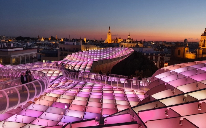 Visitors walking on illuminated Setas de Sevilla at night, Spain.