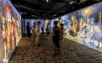 Visitors viewing immersive Mozart-themed projections at an exhibition.