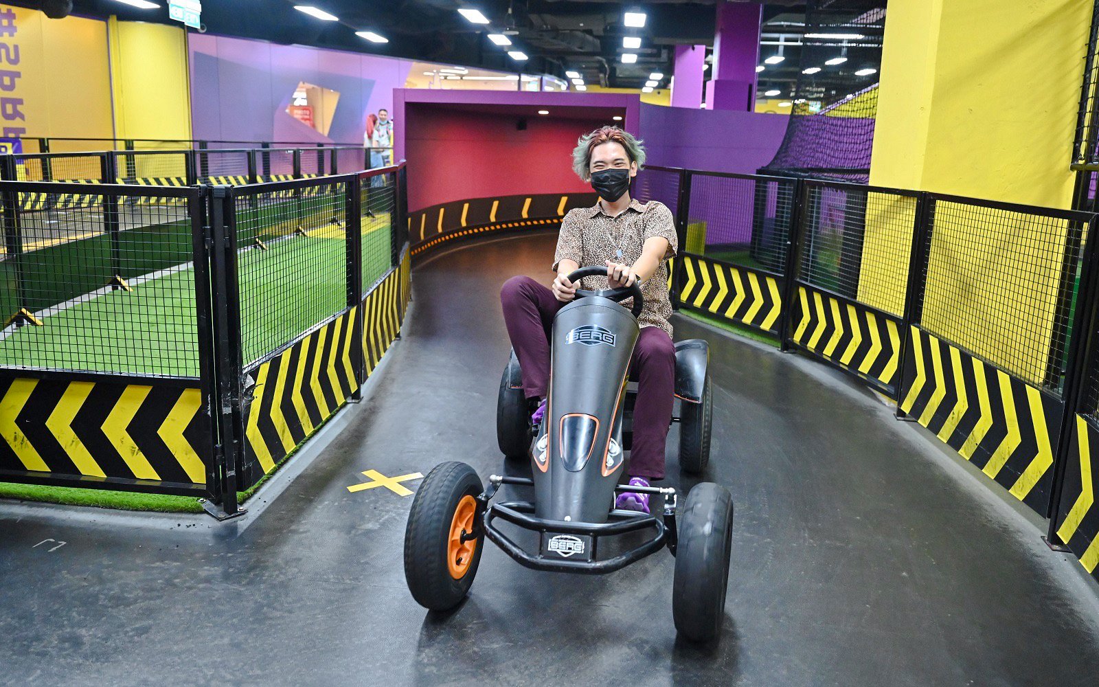 Person driving a go-kart on an indoor track at SuperPark Singapore.