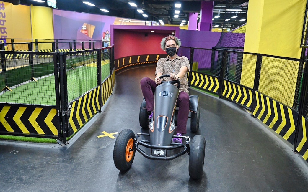 Person driving a go-kart on an indoor track at SuperPark Singapore.
