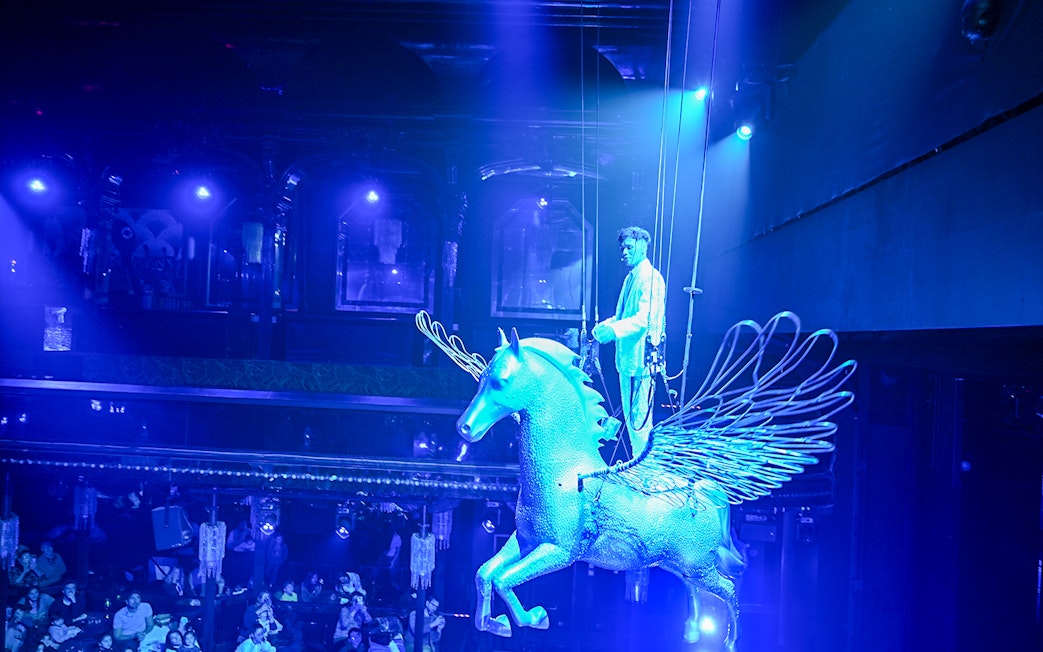 Performer on a winged horse at Paris cabaret show.