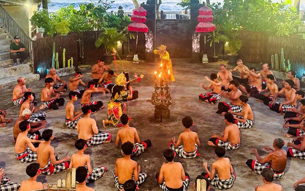 Performers in traditional Balinese attire enact a Ramayana scene, one character held aloft.