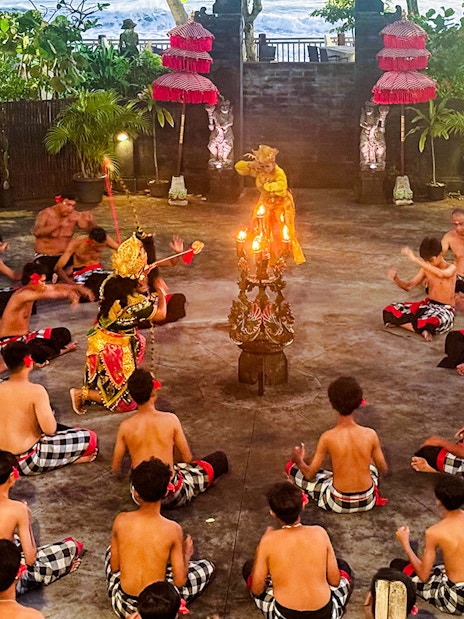 Performers in traditional Balinese attire enact a Ramayana scene, one character held aloft.