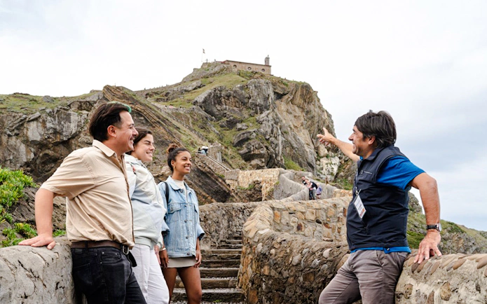 Tour guide with group at Gaztelugatxe, stone path leading to chapel, San Sebastian tour.