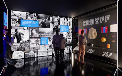 Visitors viewing exhibits at Camp Nou Barca Museum featuring Johan Cruyff memorabilia.