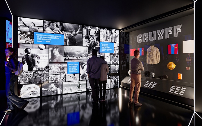 Visitors viewing exhibits at Camp Nou Barca Museum featuring Johan Cruyff memorabilia.