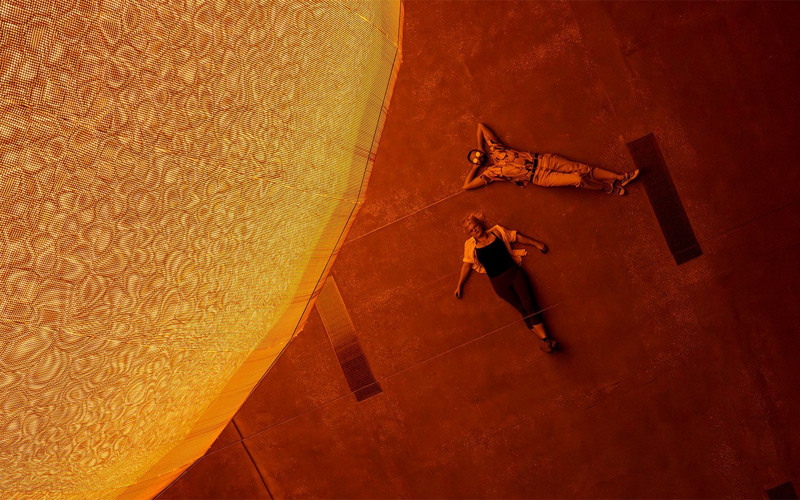 Visitors lying beneath Olafur Eliasson's sun installation at Gallery of Modern Art.