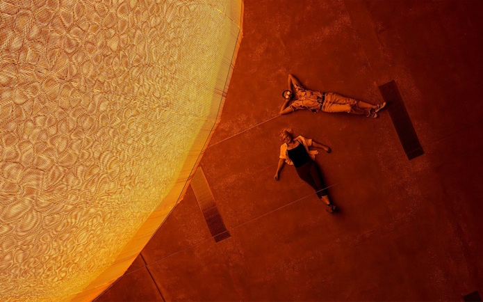 Visitors lying beneath Olafur Eliasson's sun installation at Gallery of Modern Art.