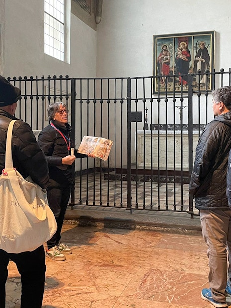 Tour guide explaining a painting to tourists in a historic building.