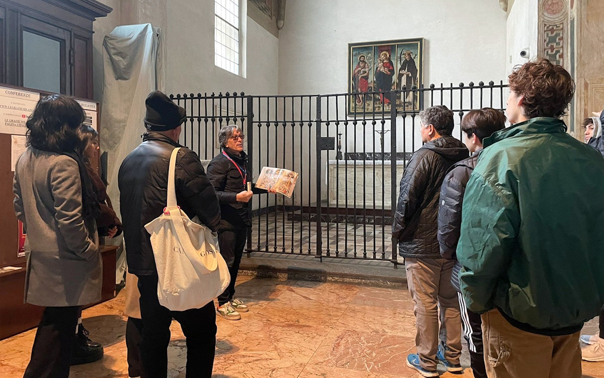 Tour guide explaining a painting to tourists in a historic building.