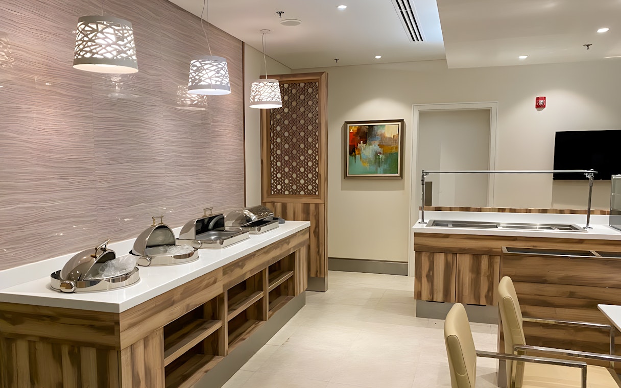 Premium lounge buffet area at Jeddah Airport with modern decor and food stations.