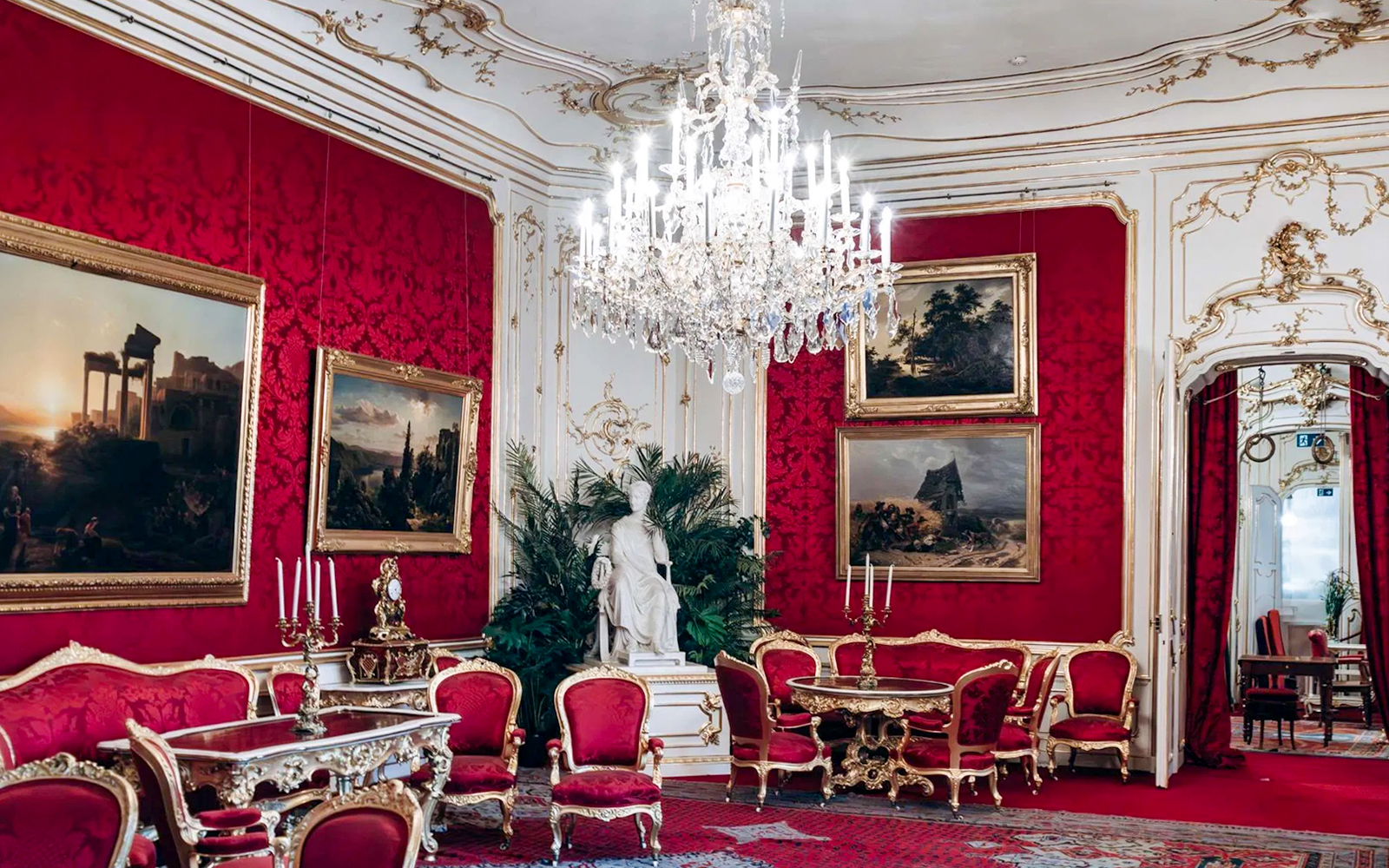 Imperial Apartments in Hofburg Palace, Vienna, featuring ornate red decor and chandeliers.