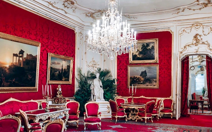 Imperial Apartments in Hofburg Palace, Vienna, featuring ornate red decor and chandeliers.