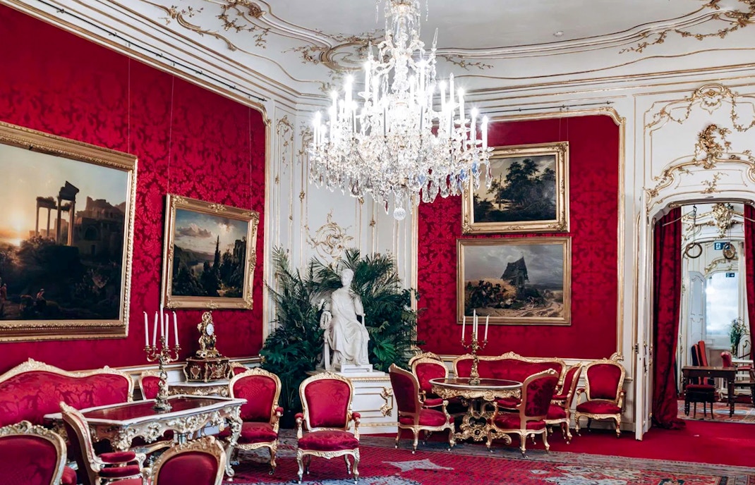 Imperial Apartments in Hofburg Palace, Vienna, featuring ornate red decor and chandeliers.