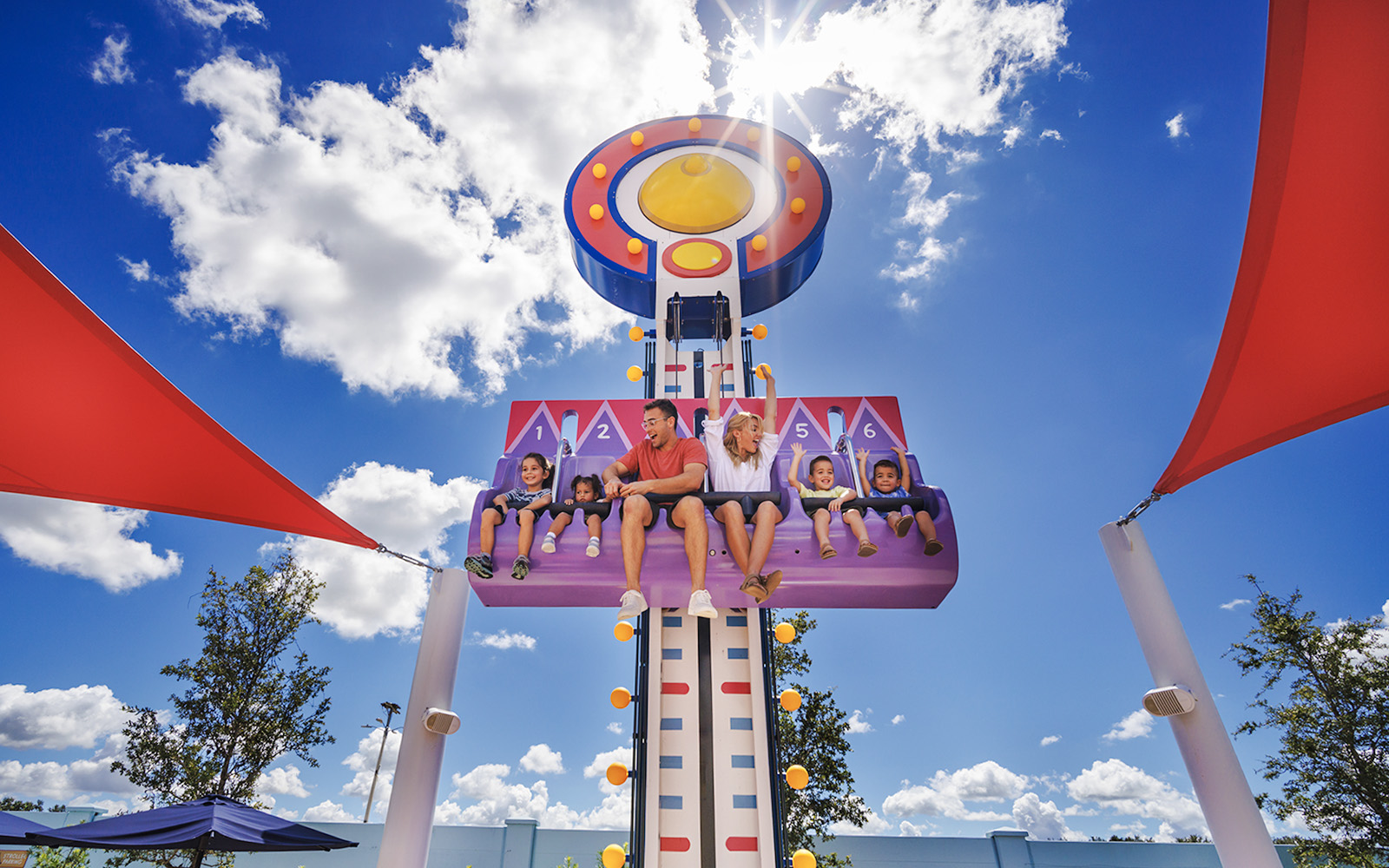 Children and adults on a ride at Peppa Pig Theme Park, Florida under a sunny sky.