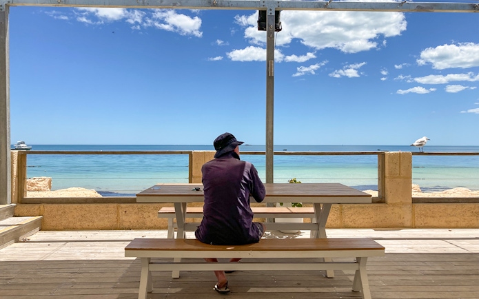 Person sitting at a picnic table overlooking the ocean on Australia's Pinnacles tour.