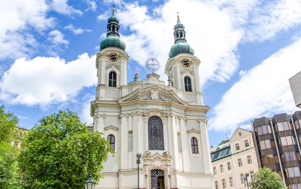 Church of Saint Mary Magdalene with twin towers in Karlovy Vary under a blue sky.