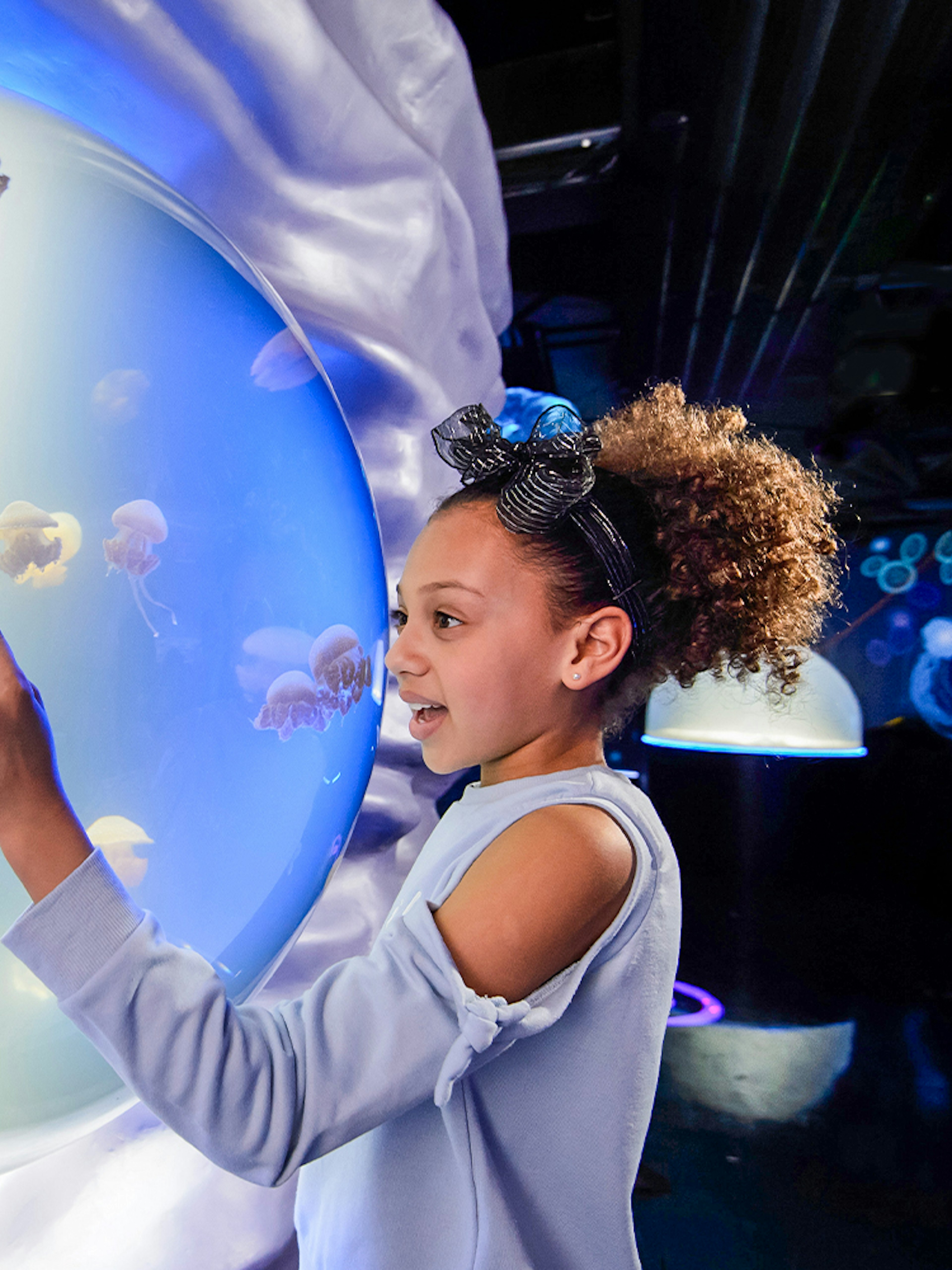 Child interacting with jellyfish exhibit at SEA LIFE London.