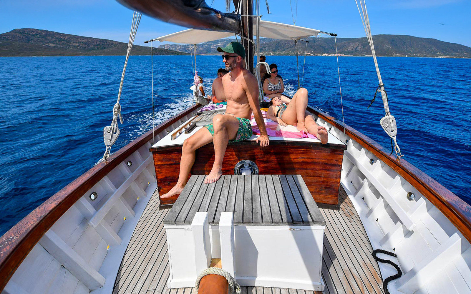 Sailing on a wooden boat towards Asinara Island with passengers relaxing on deck.