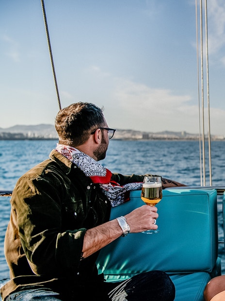 Couple enjoying drinks on a catamaran with Barcelona skyline in the background.