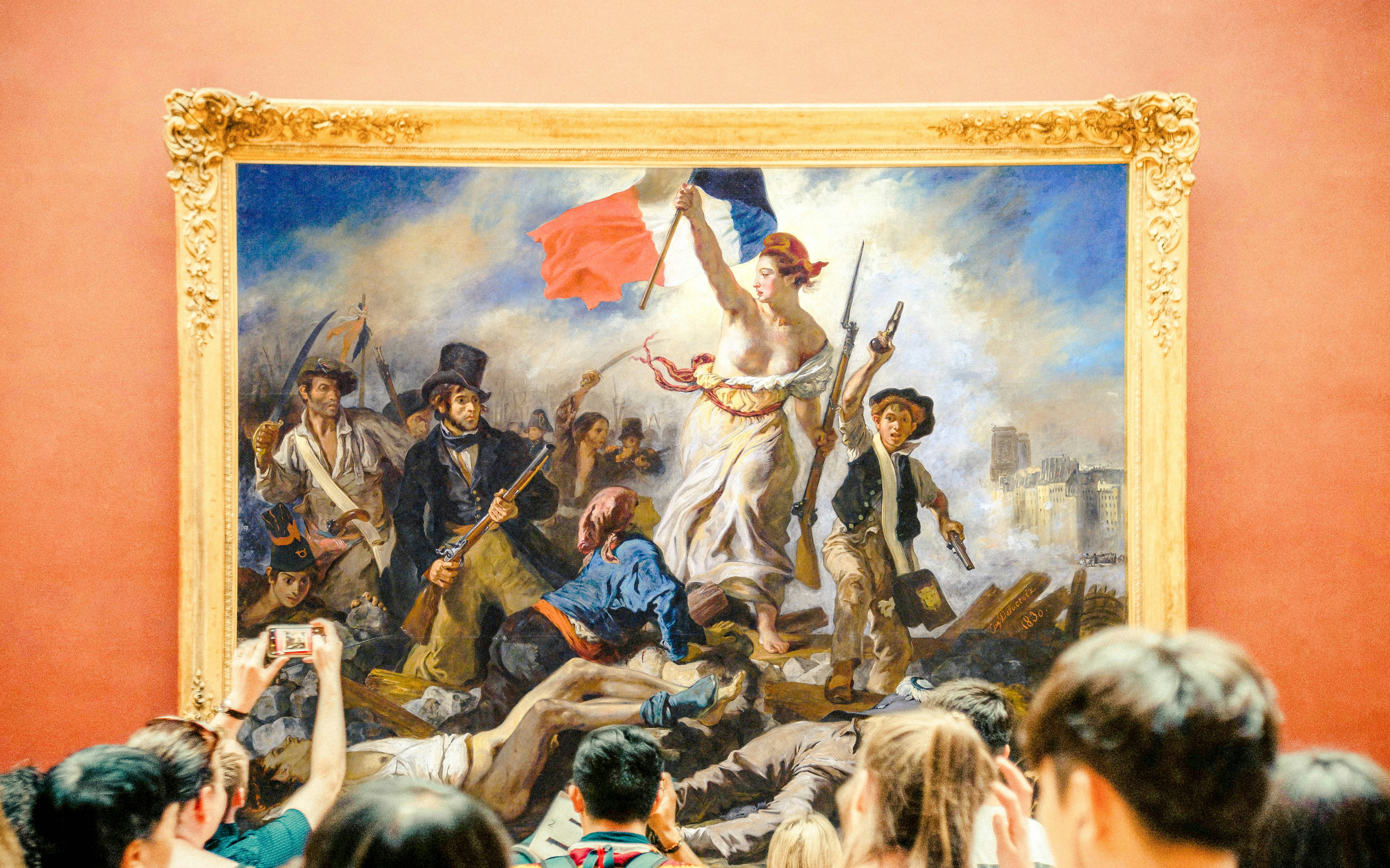Tourists with guide viewing "Liberty Leading the People" painting at Louvre Museum, Paris.