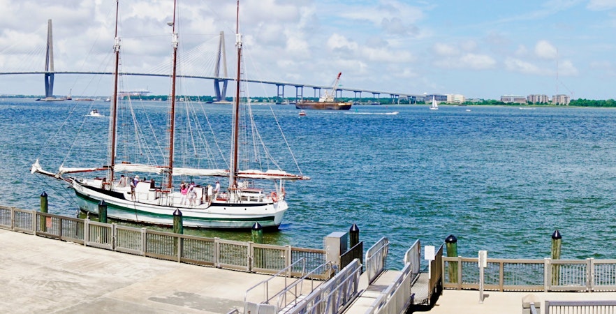Charleston harbor view with sailboat and Arthur Ravenel Jr Bridge in the background.