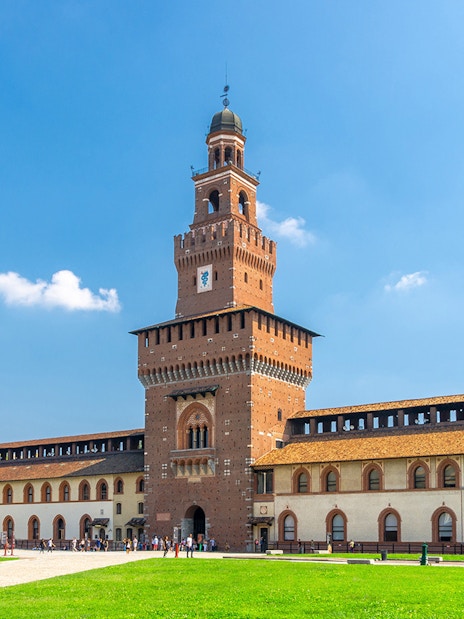 Sforza Castle courtyard in Milan with tourists exploring historic architecture.