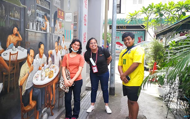 Tourists posing by a mural in Chinatown during the Guided City Highlights Tour.